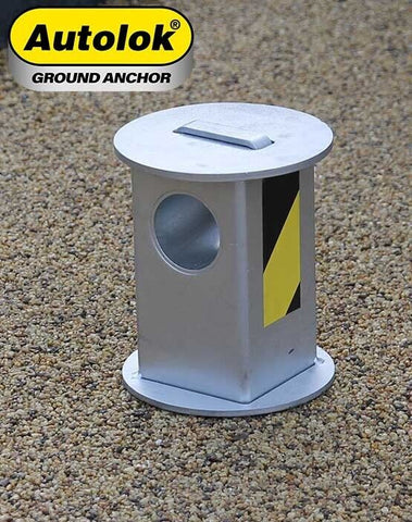 Autolok telescopic motorcycle security ground anchor with a silver finish and yellow warning sticker, set in a concrete surface.